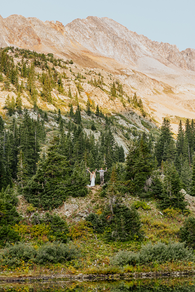 Anyeli and Alex celebrating their elopement with a joyful moment on top of a mountain in Crested Butte, Colorado.