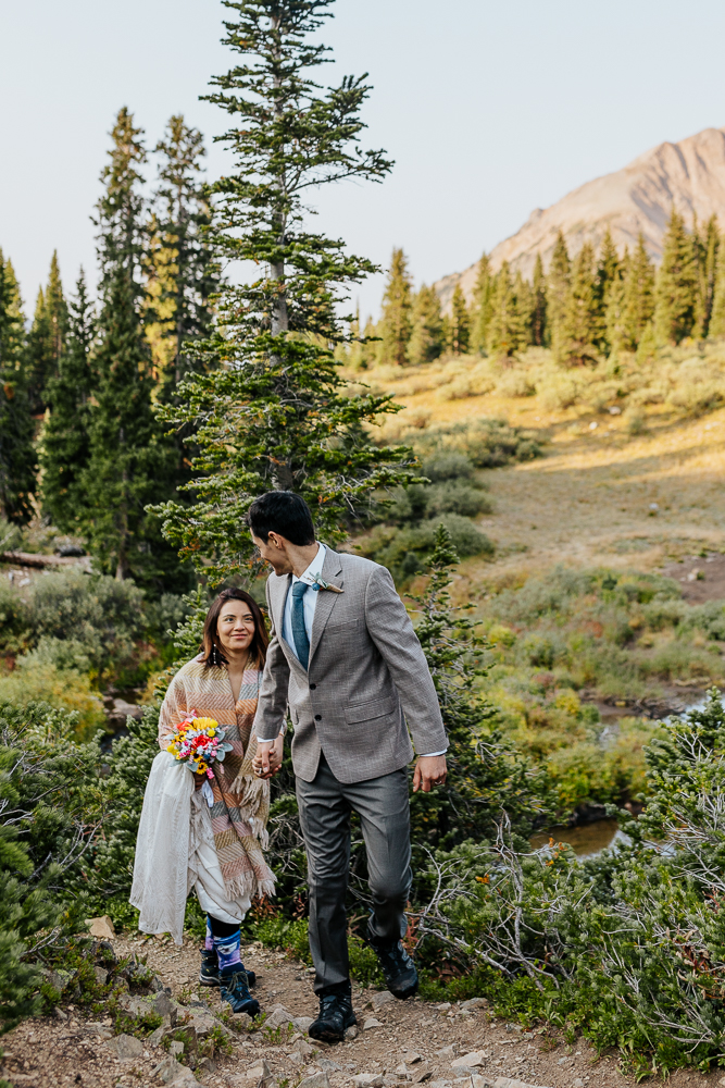 Anyeli and Alex hiking up a mountain trail in Crested Butte, during their adventure elopement at Copper Lake.