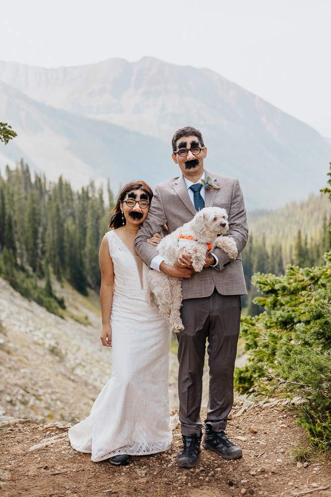 Anyeli and Alex having fun and posing with silly glasses during their intimate elopement at Copper Lake, Crested Butte.