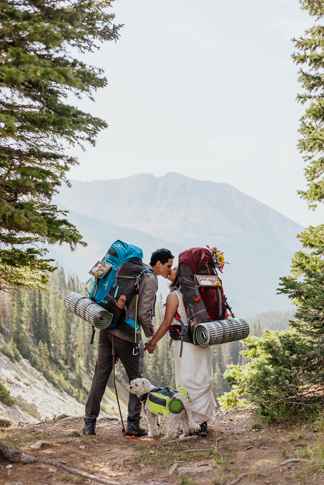 Anyeli and Alex sharing a kiss while wearing their backpacks, capturing a moment of love during their adventure elopement in Crested Butte, Colorado.