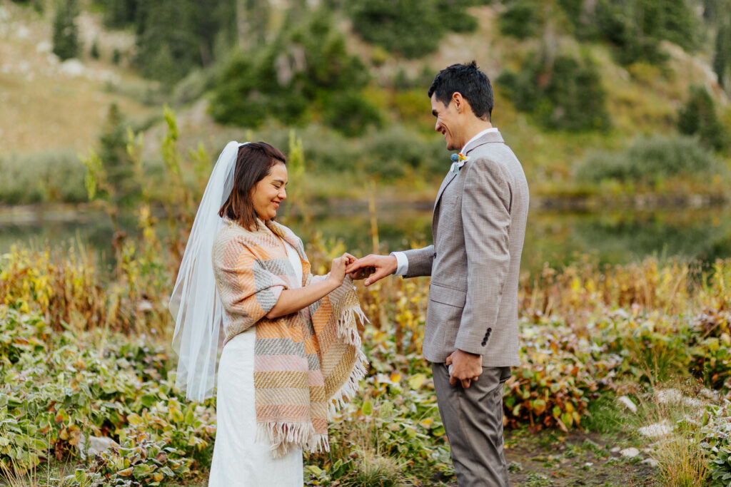 The bride lovingly placing the ring on the groom’s finger during their sunrise elopement ceremony at Copper Lake, Crested Butte.