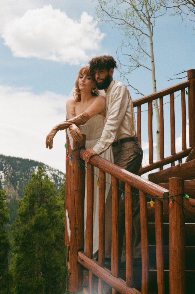 Film portrait of a couple posing on a wooden log cabin staircase during their intimate Leadville elopement.