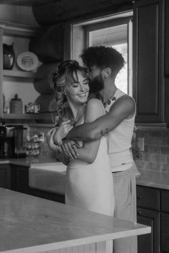 Colorado elopement couple sharing a warm cuddle in their PJs while relaxing in the cabin kitchen.