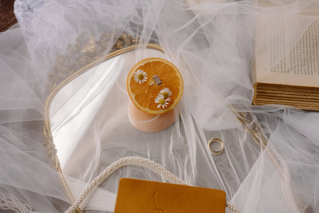 Bridal detail flatlay for a Colorado mountain elopement featuring wedding rings, citrus accents, and the bride’s heels and veil.