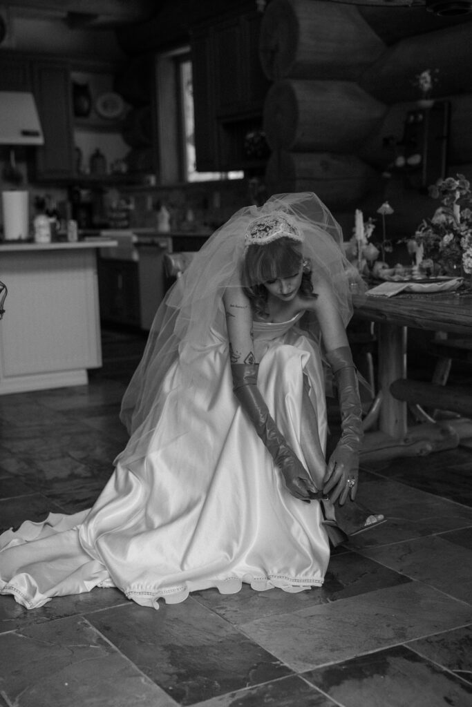 Adventure elopement bride preparing for her day, tying her wedding shoes in the cozy cabin.