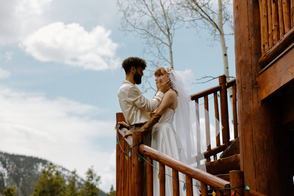 The groom gently holds his bride’s face in his hands during a tender moment of their Colorado elopement.