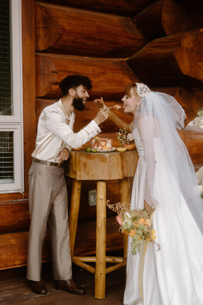 Colorado cabin elopement couple enjoying their heart-shaped wedding cake together.