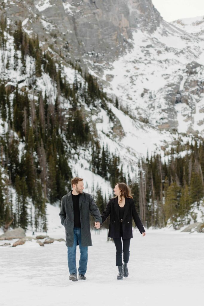 Couple walking across the ice of a frozen Dream Lake in Colorado.