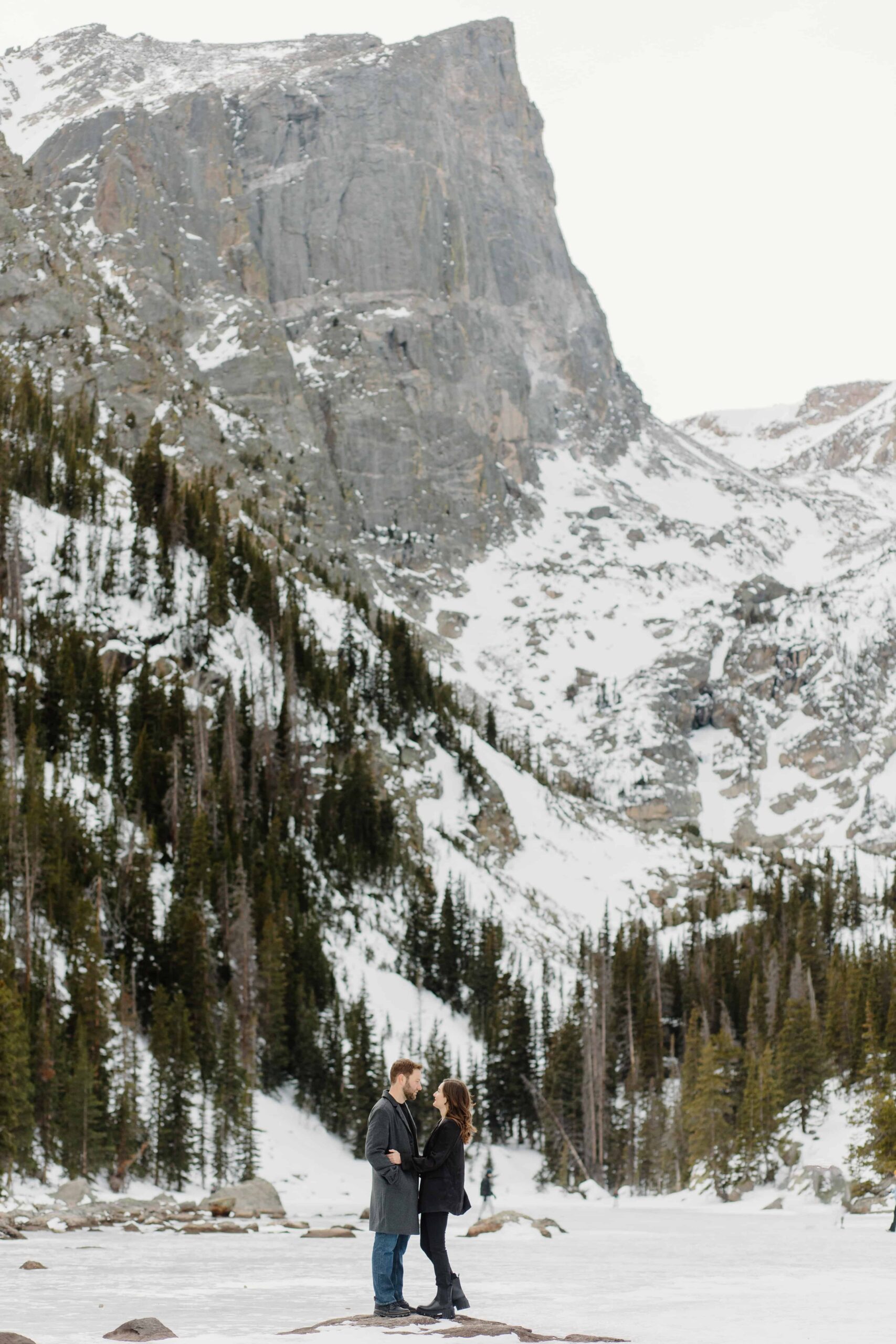 Couple standing in front of snow-capped peaks in Rocky Mountain National Park.