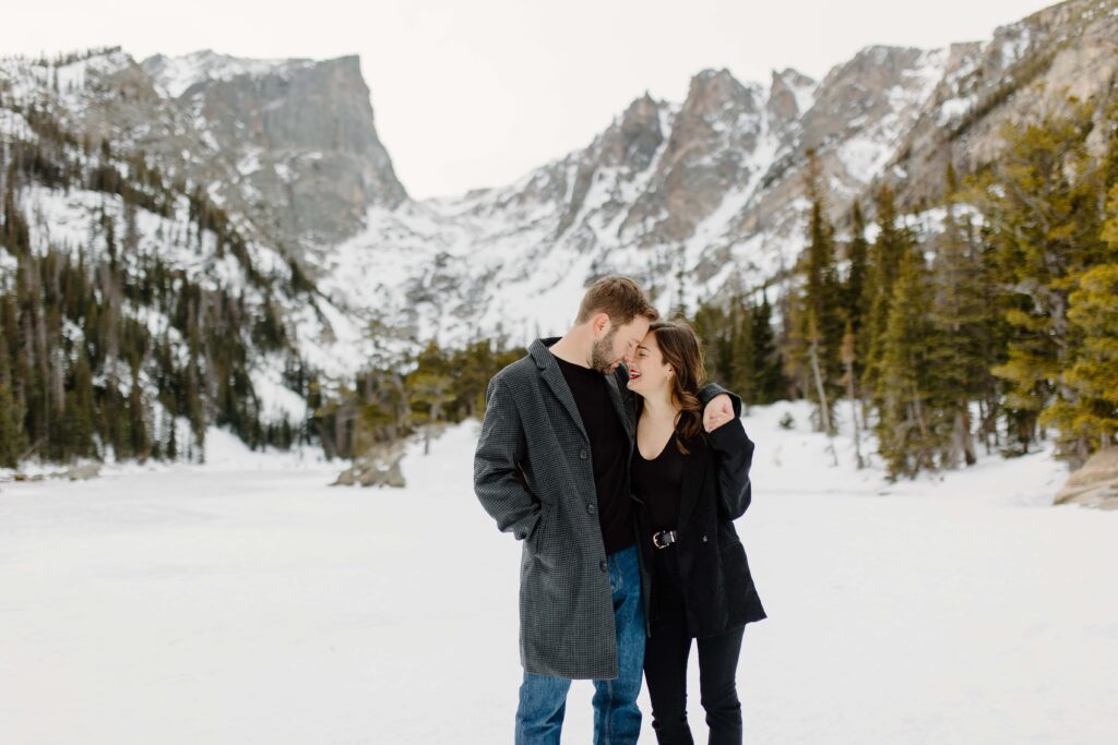 Cozy couple embracing while surrounded by the vast white wilderness of the Rockies.