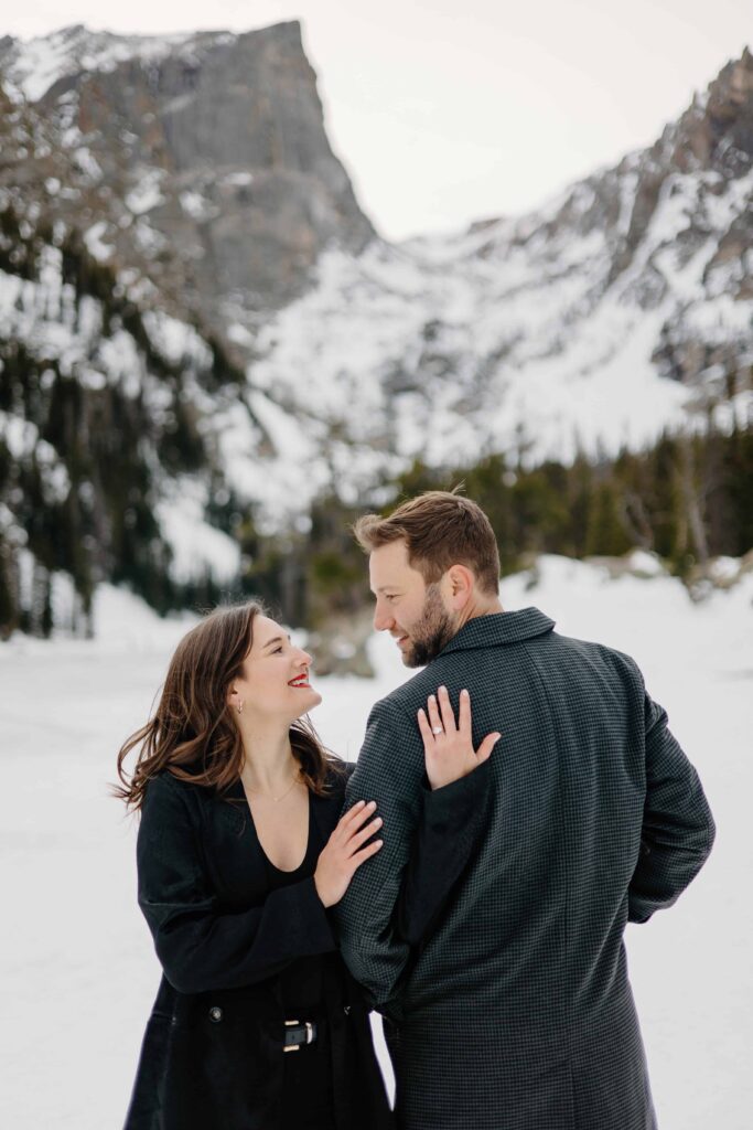 Annie and Josh snuggling close and looking at each other against a snowy mountain backdrop.