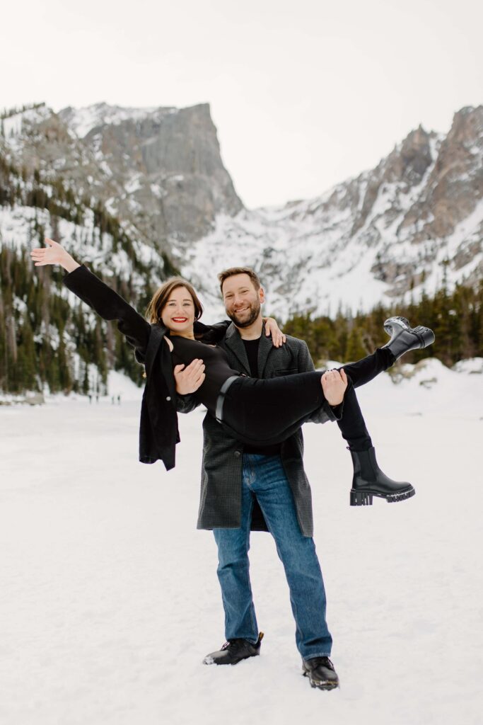 Josh lifting Annie up in the snow while she smiles with her arms out in a joyful moment.