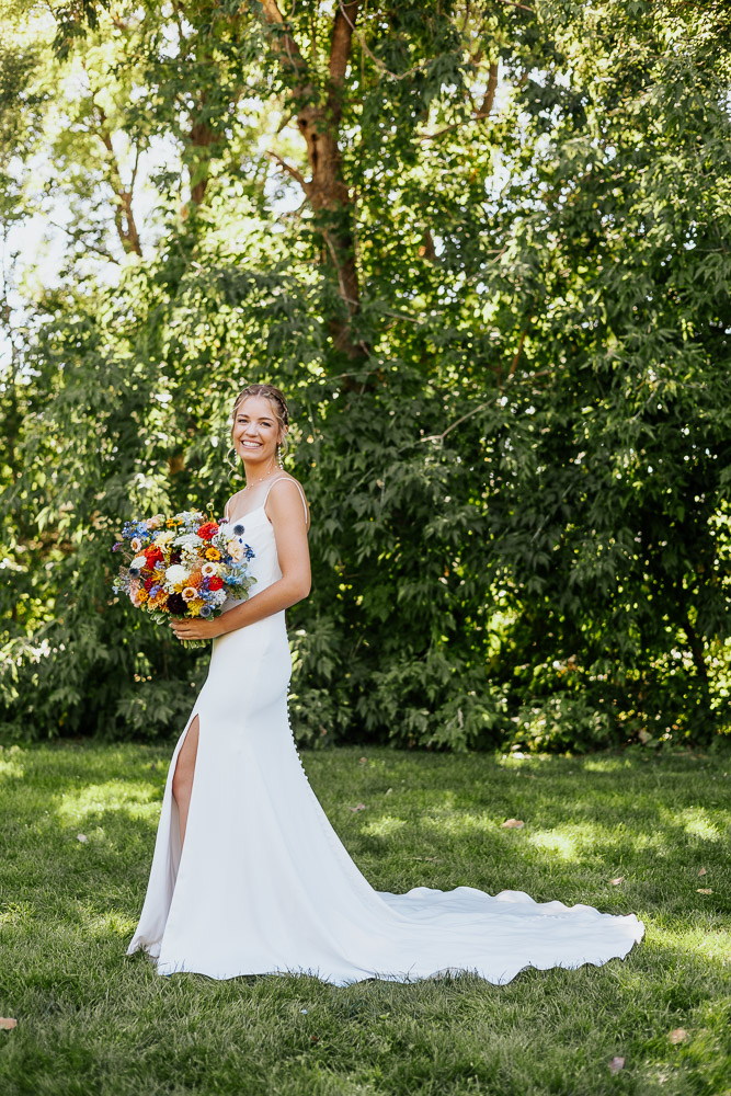 Bride striking a pose for a wedding photo in lush garden surroundings.