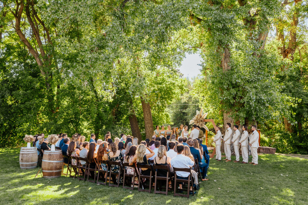 Wide shot of the wedding ceremony, capturing the venue’s scenic beauty and guests at Lyons Farmette.