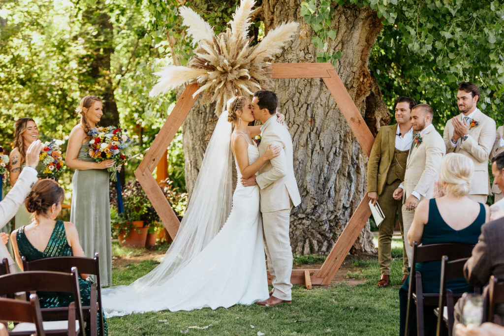 Bride and groom share their first kiss as a married couple during the ceremony at Lyons Farmette.