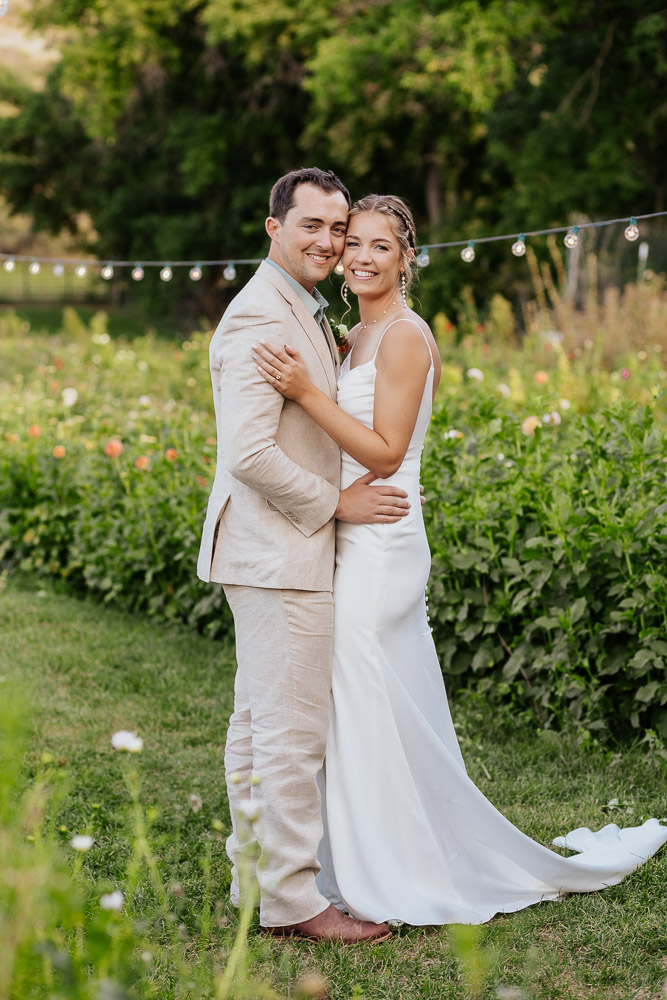 Bride and groom posing for a wedding photo in the vibrant flower garden at Lyons Farmette.