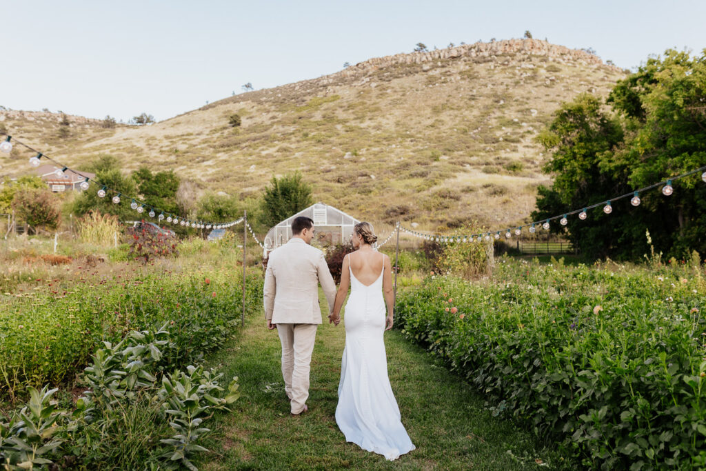 Gina and Spencer walk hand in hand through the beautiful flower garden at Lyons Farmette, Lyons, Colorado.