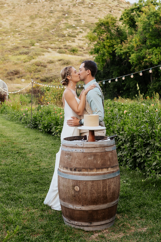 Bride and groom share a kiss after cutting their wedding cake at Lyons Farmette.