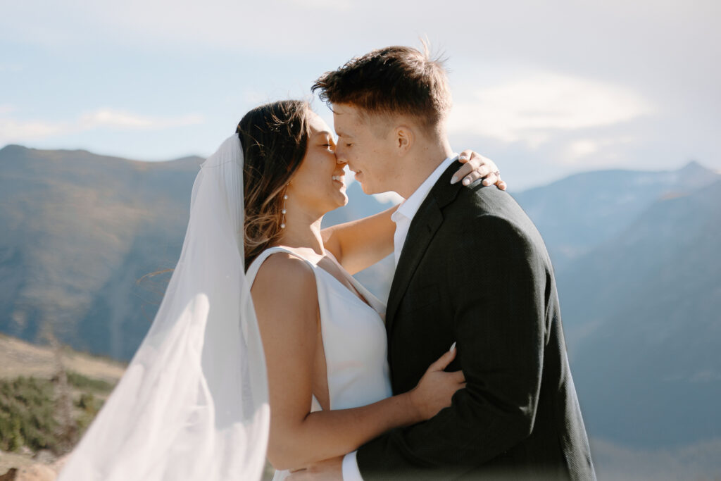 A bride and groom share a romantic kiss on Trail Ridge Road in Rocky Mountain National Park during their day after session in Colorado's stunning mountain scenery.