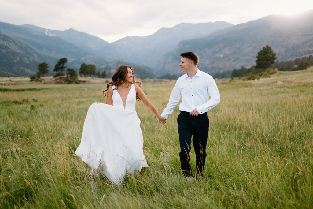 A playful bride and groom run towards the camera with joy during their Estes Park day after session in Colorado.