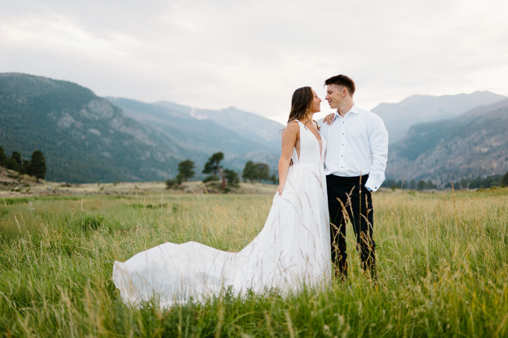 A bride and groom smile warmly at each other in Moraine Valley, surrounded by the natural beauty of Estes Park, Colorado.