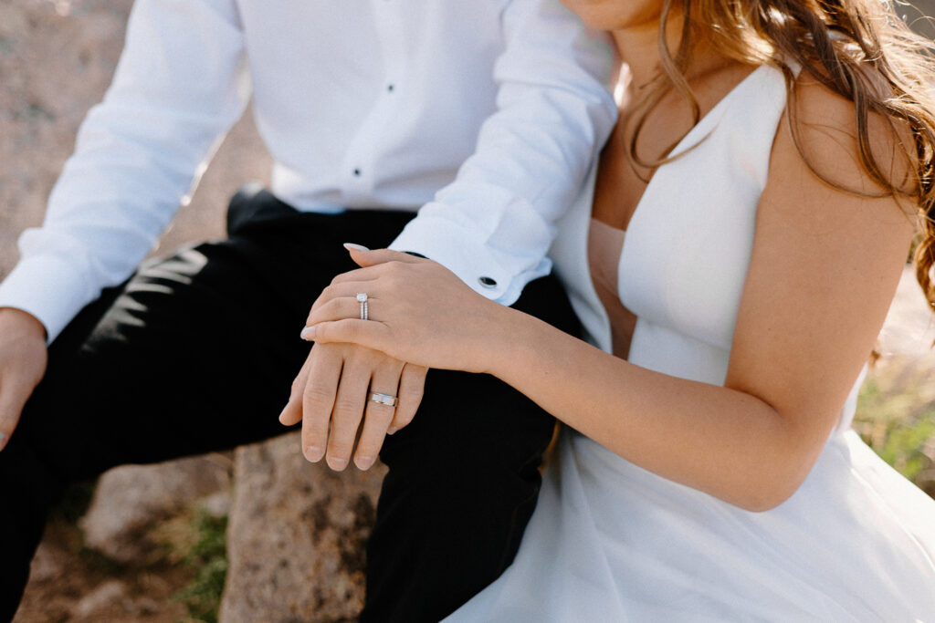 An up-close shot of a bride and groom holding hands, highlighting their wedding rings during a day after session in Rocky Mountain National Park.