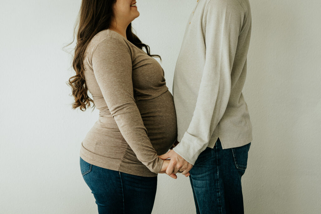 A couple holds hands during their maternity session at Sugarhill Studio in Longmont, Colorado, capturing a beautiful moment of connection and anticipation.