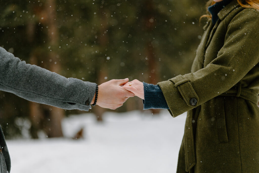 A bride and groom hold hands, showing off their ring during their engagement session at Echo Lake.