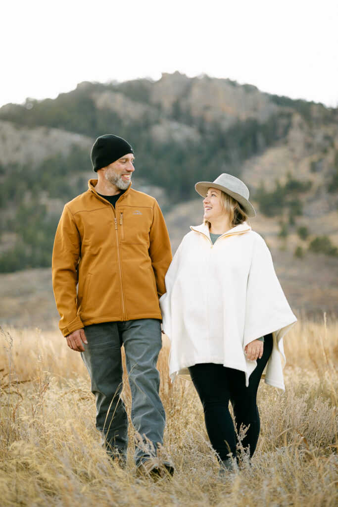 A husband and wife hold hands and walk towards the camera during their Family Photo Session in Fort Collins, Colorado.